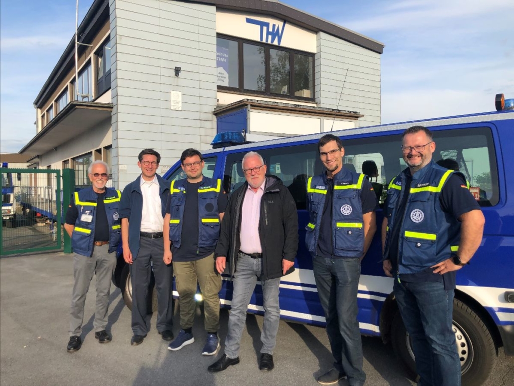 Wolfgang Hellmich mit Mitgliedern des THW, in einer Reihe vor einem blauen Einsatzfahrzeug